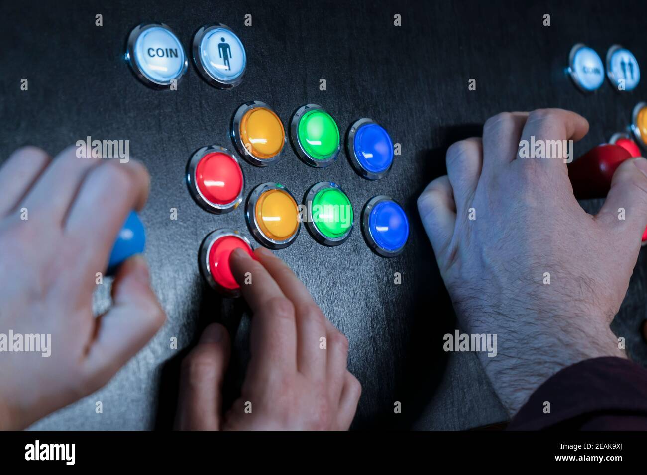 Closeup view of two people hands playing arcade vintage video games.Gamepad with joystick and many colorful buttons .Gaming concept. Stock Photo