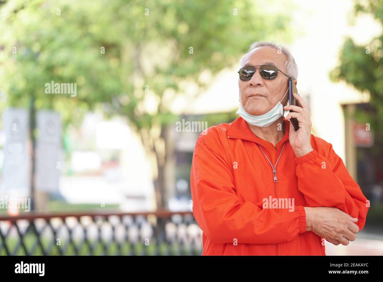 asian old asian elderly senior elder man talking on smart mobile phone outdoor Stock Photo
