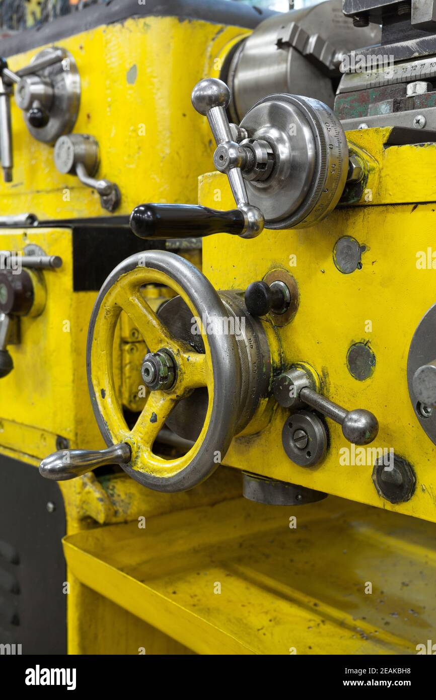 Old yellow lathe machine with a lot of handles. Stock Photo