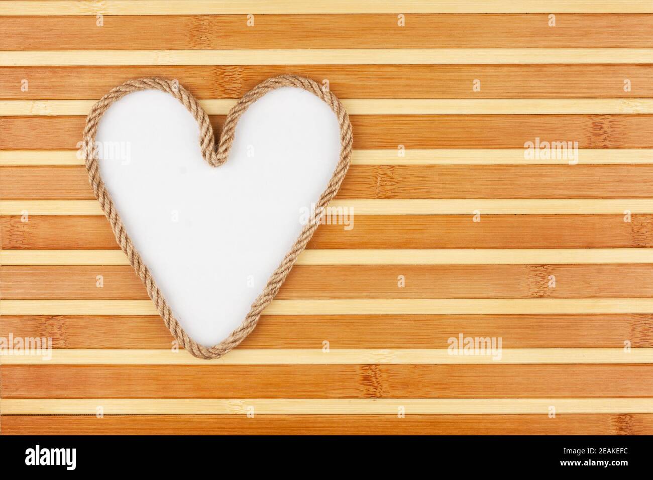 Symbolic heart made of rope lying on a bamboo mat Stock Photo