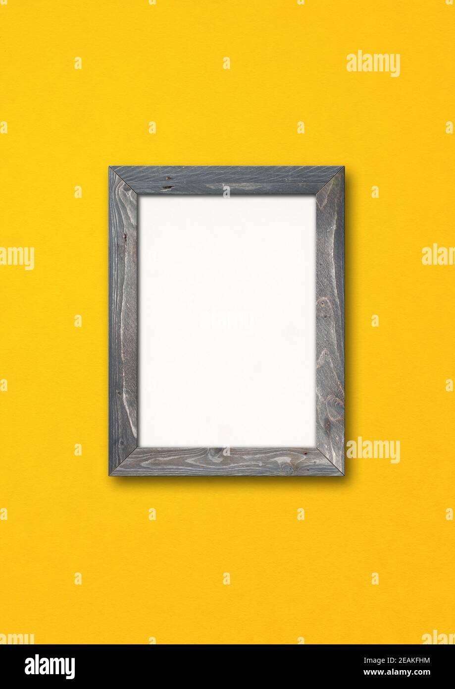 Old rustic wooden picture frame hanging on a yellow wall Stock Photo