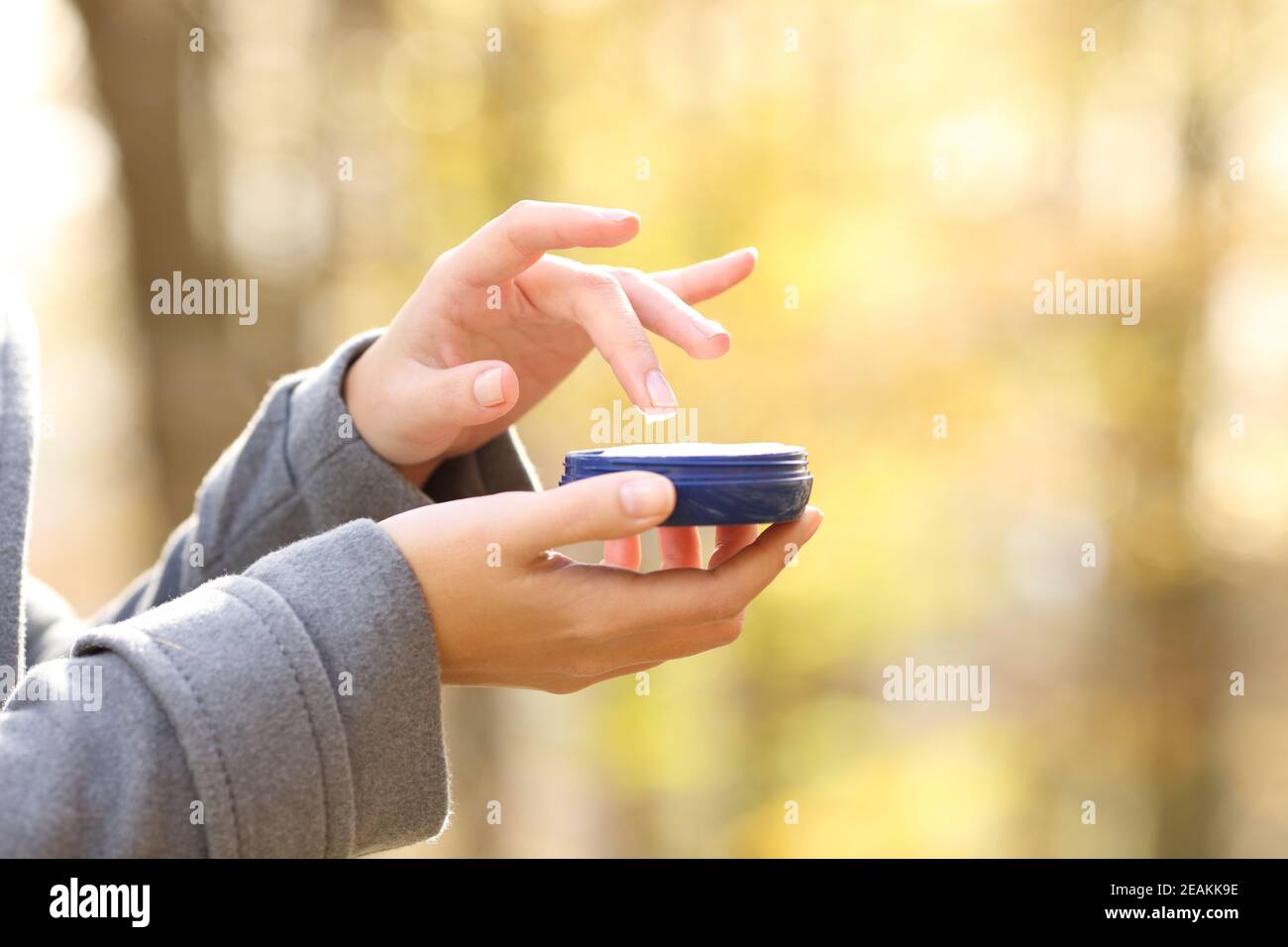 Woman hand holding moisturizer cream bottle in fall Stock Photo
