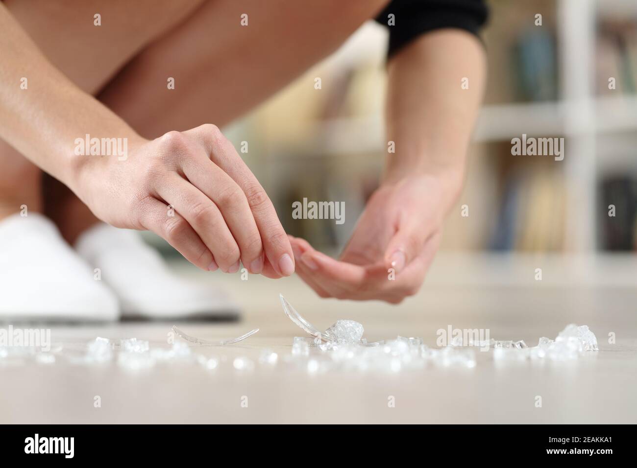 Woman hands picking up broken glass on the floor at home Stock Photo