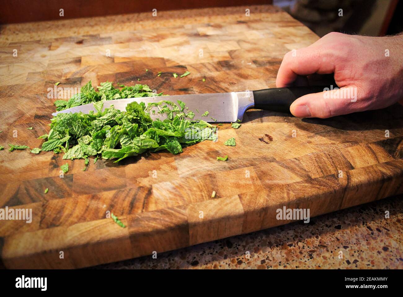 Closeup of a hand holding a knife cutting green mint Stock Photo