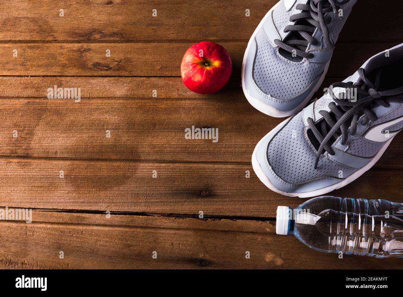 pair sports shoes, bottle water and red apple on wood table Stock Photo