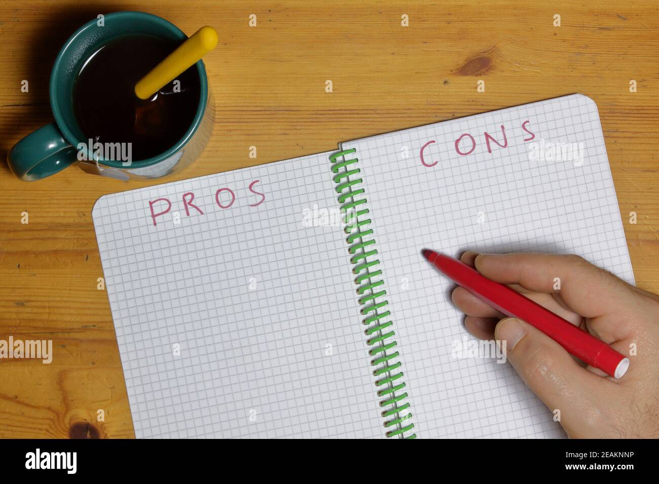 pros cons list in a notebook and man hand with red marker writing Stock Photo