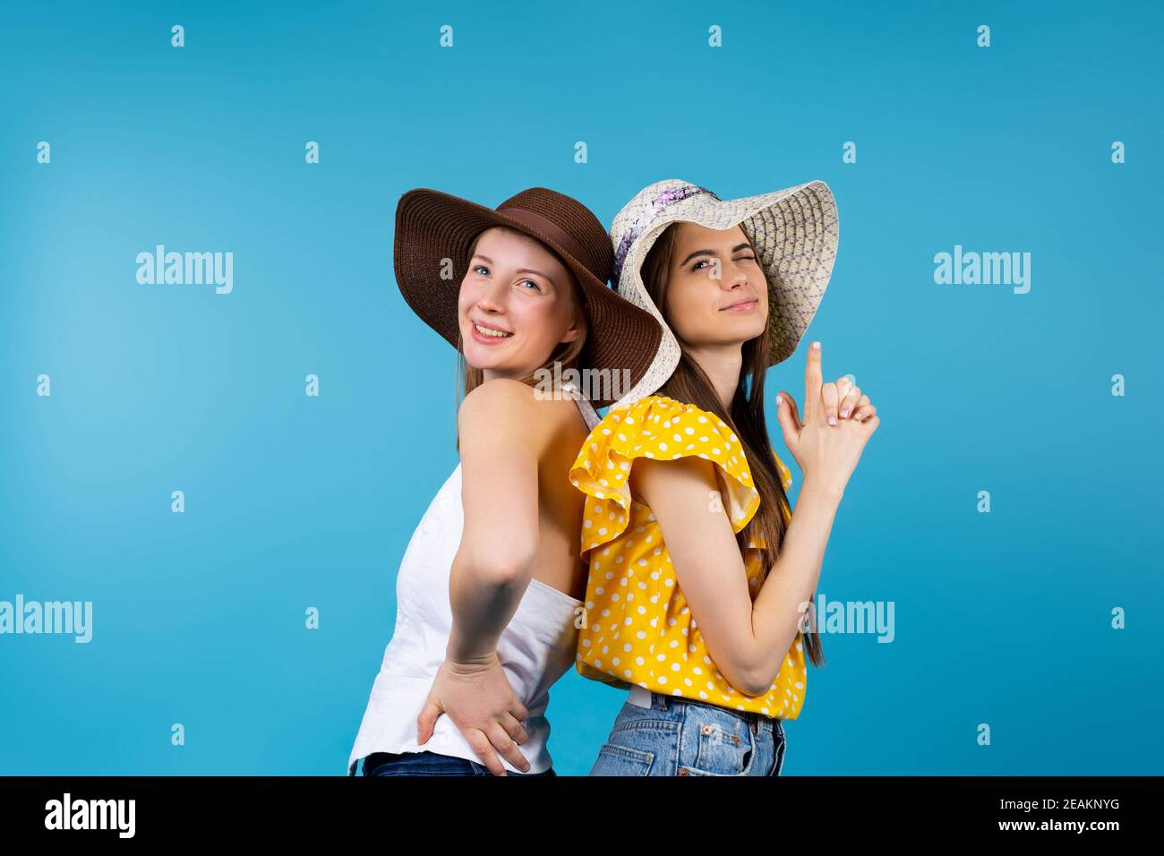 Summer caucasian girls sitting back to back, looking up, showing ...