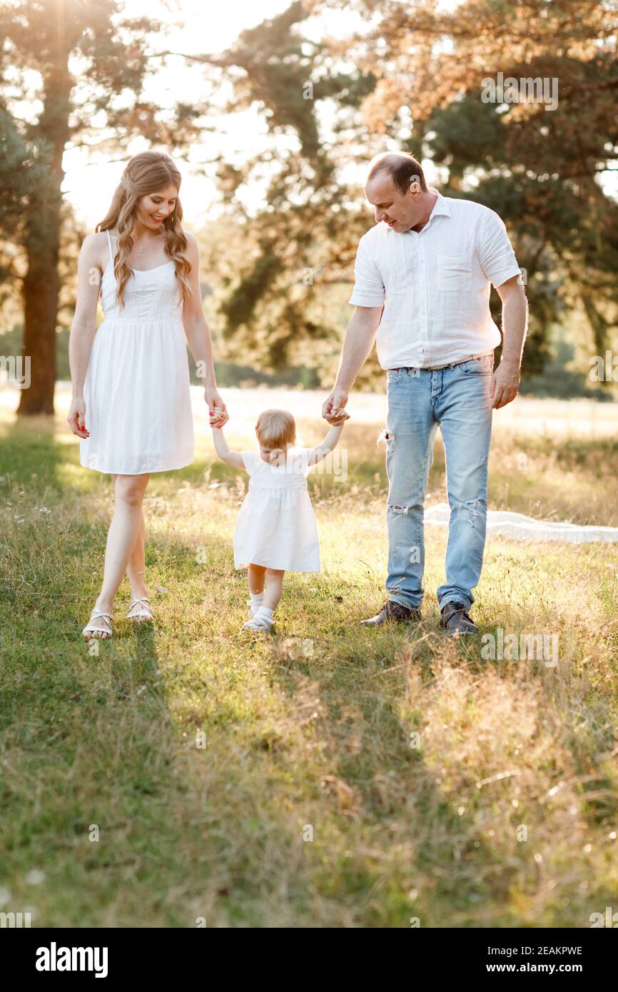 Portrait of happy family. Mom, dad and daughter walk in the park in ...