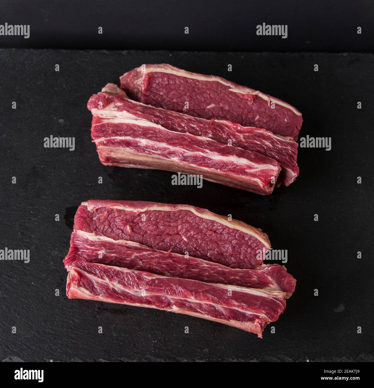 raw meat photographed on a wooden cutting board with a black background Stock Photo