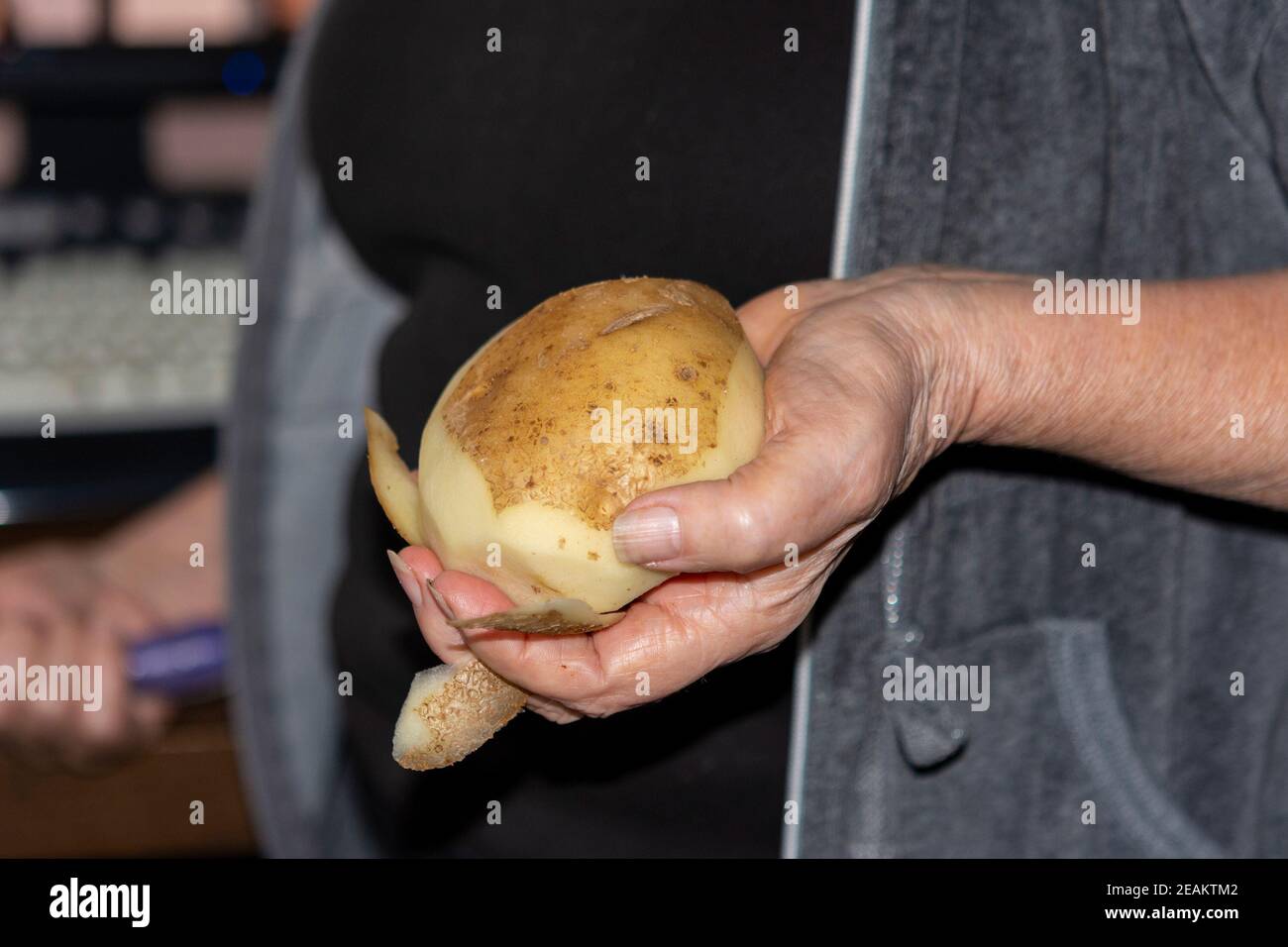 Unpeeled potatoes in hand Stock Photo
