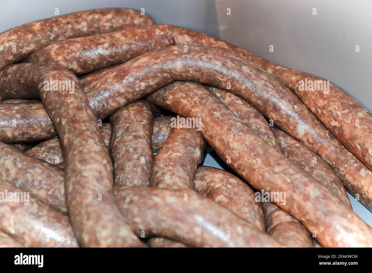 Closeup of raw sausage in casings resting in a tub Stock Photo