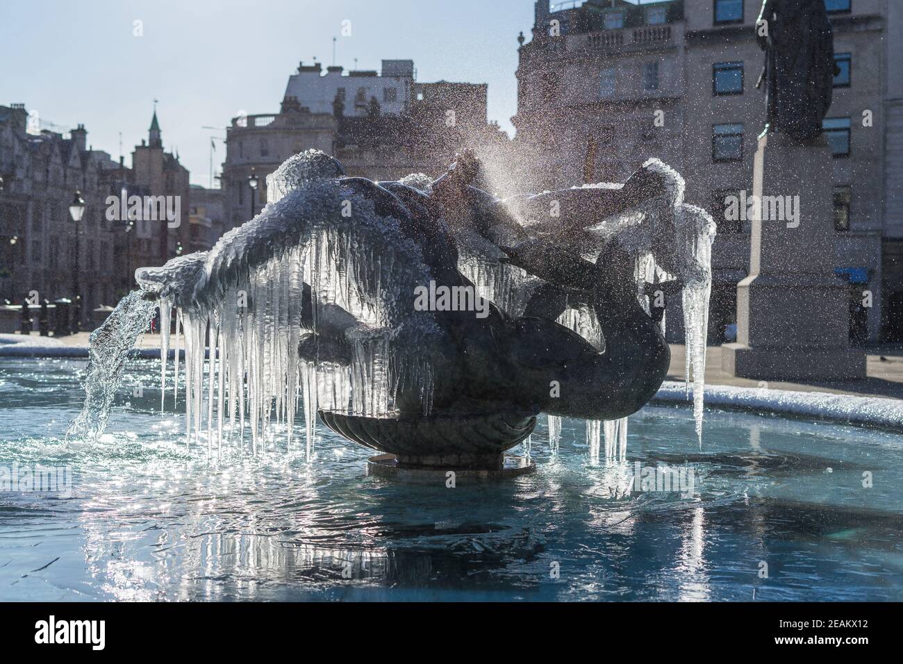 Frozen fountain statues of Trafalgar Square in London. Icicles mystically hanging off bronze water fountain Stock Photo