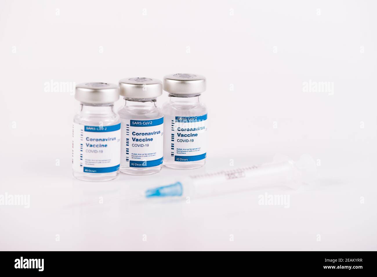 three Covid-19 vaccine vials with white background and a syringe to ...