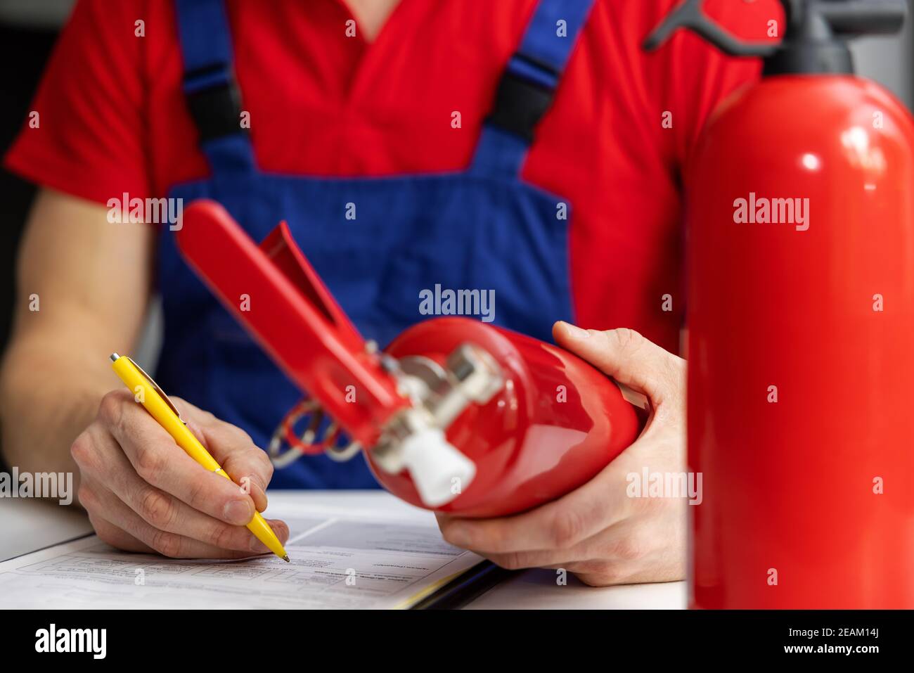 fire safety equipment control - service engineer checking extinguisher condition and writing documents Stock Photo