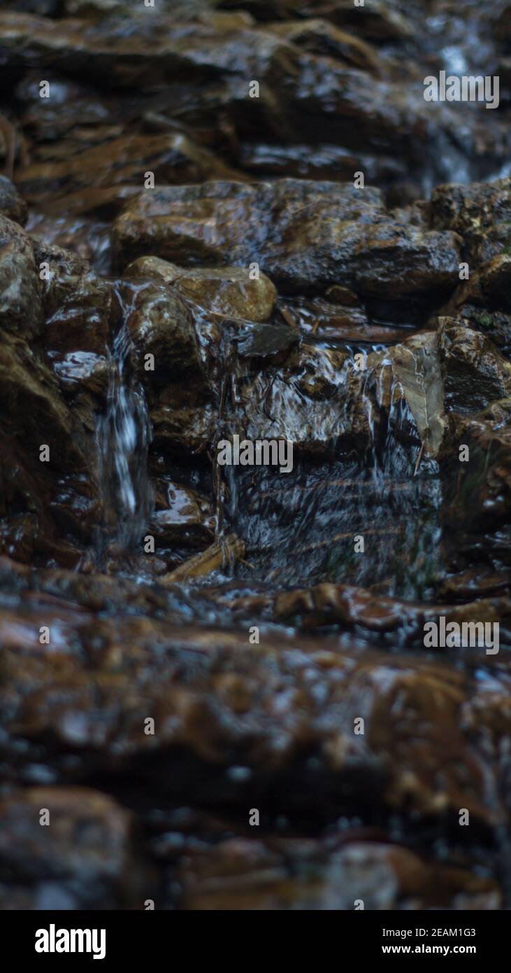 Close up of mountain river flows between picturesque summer stones. Rocks in the mountains with water flowing Stock Photo