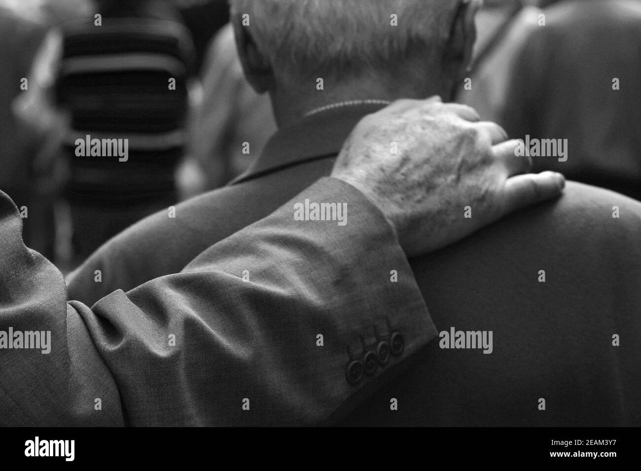 Grayscale shot of a wrinkled hand on senior man's soldier - the concept of frienship Stock Photo