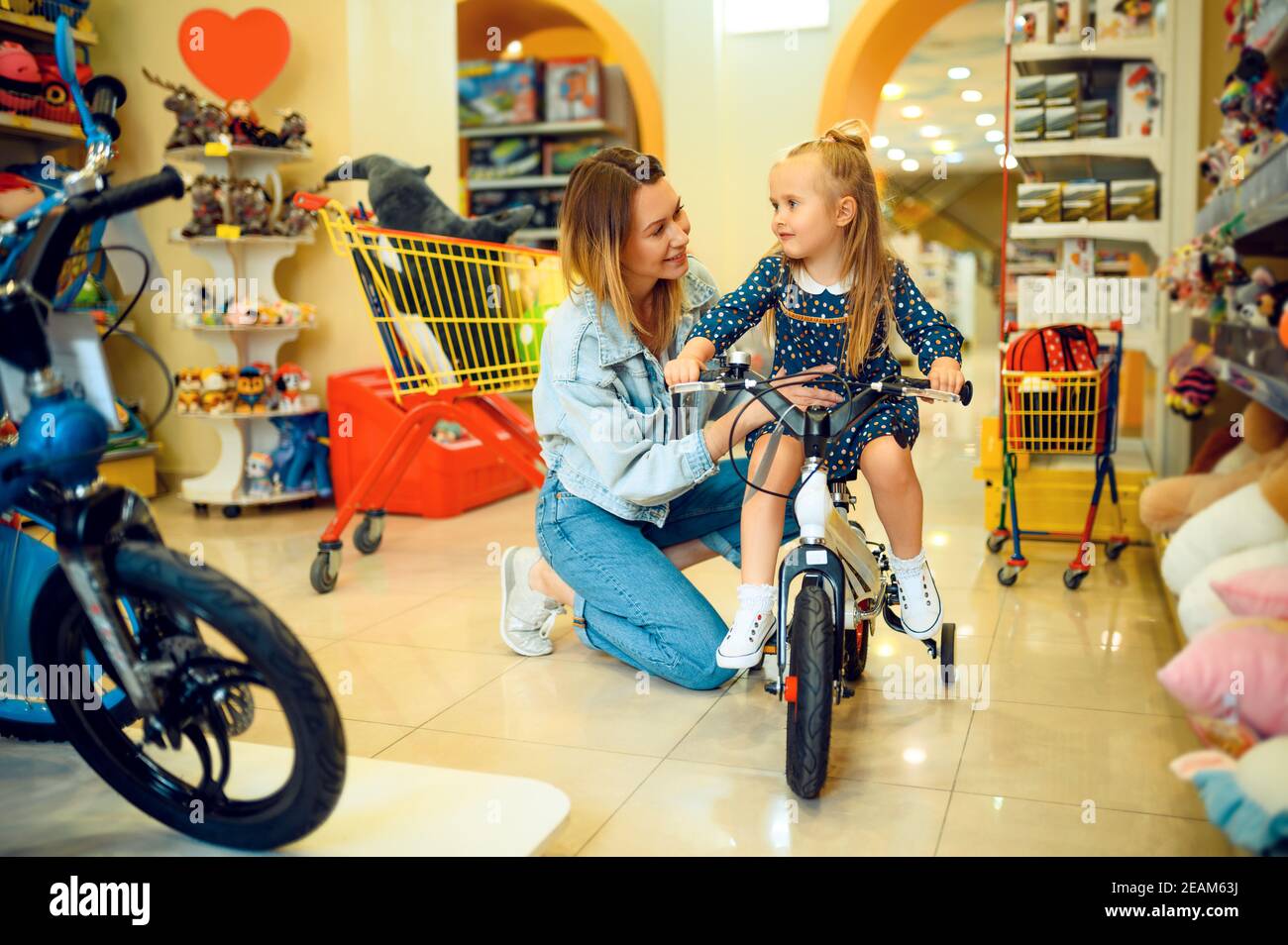Mom and little girl buying bicycle in kid's store Stock Photo Alamy