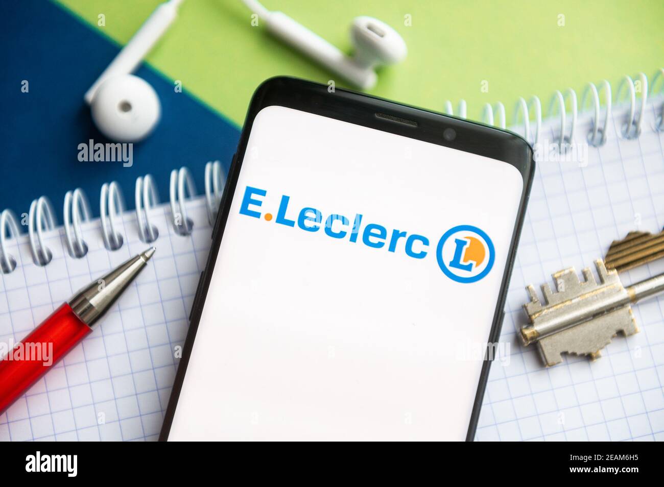 In this photo illustration, a E. Leclerc logo seen displayed on a smartphone  with a pen, key, book and headsets in the background Stock Photo - Alamy