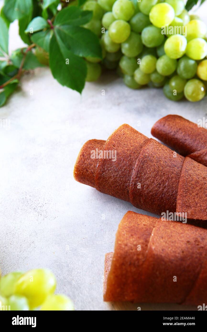 Natural light grape marshmallow is rolled into a tube. Natural product without preservatives. Food for vegetarians. Photo on a light background. View from above. Stock Photo