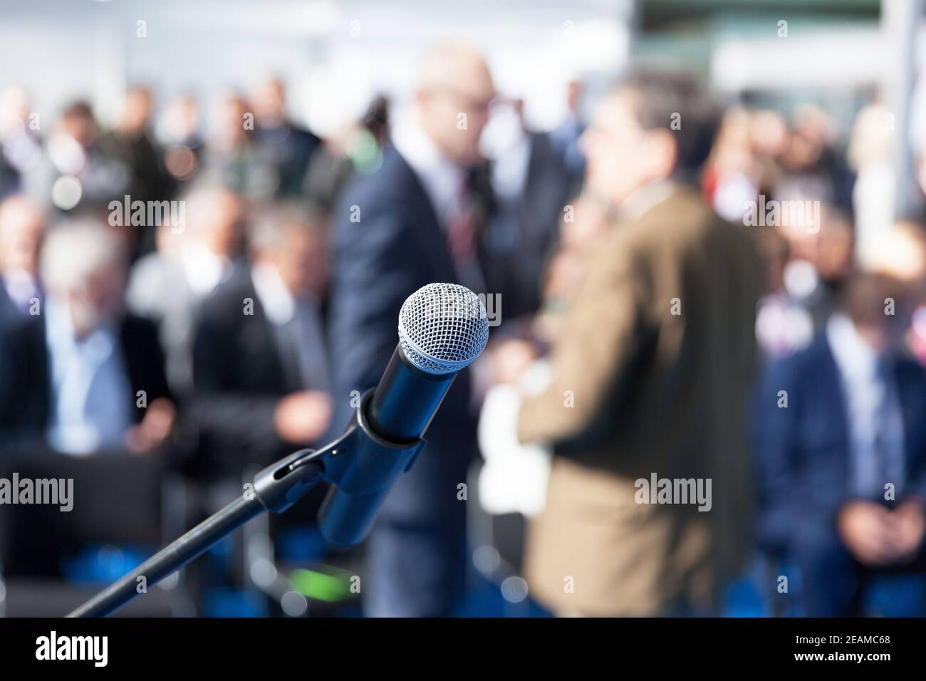 Business conference or corporate presentation. Microphone in focus against blurred audience. Stock Photo