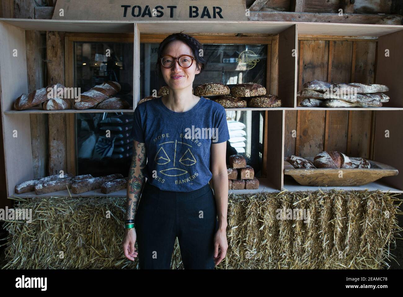 GREAT BRITAIN / England / Hertfordshire /Woman with t-shirt ' More Bakers Less Bankers standing in front artisan bread . Stock Photo