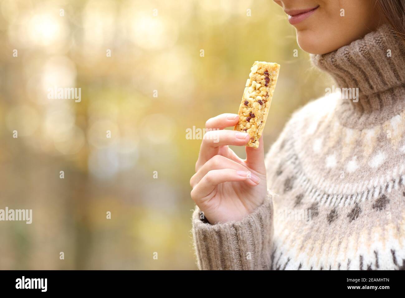 Woman holding a cereal bar ready to eat in autumn Stock Photo