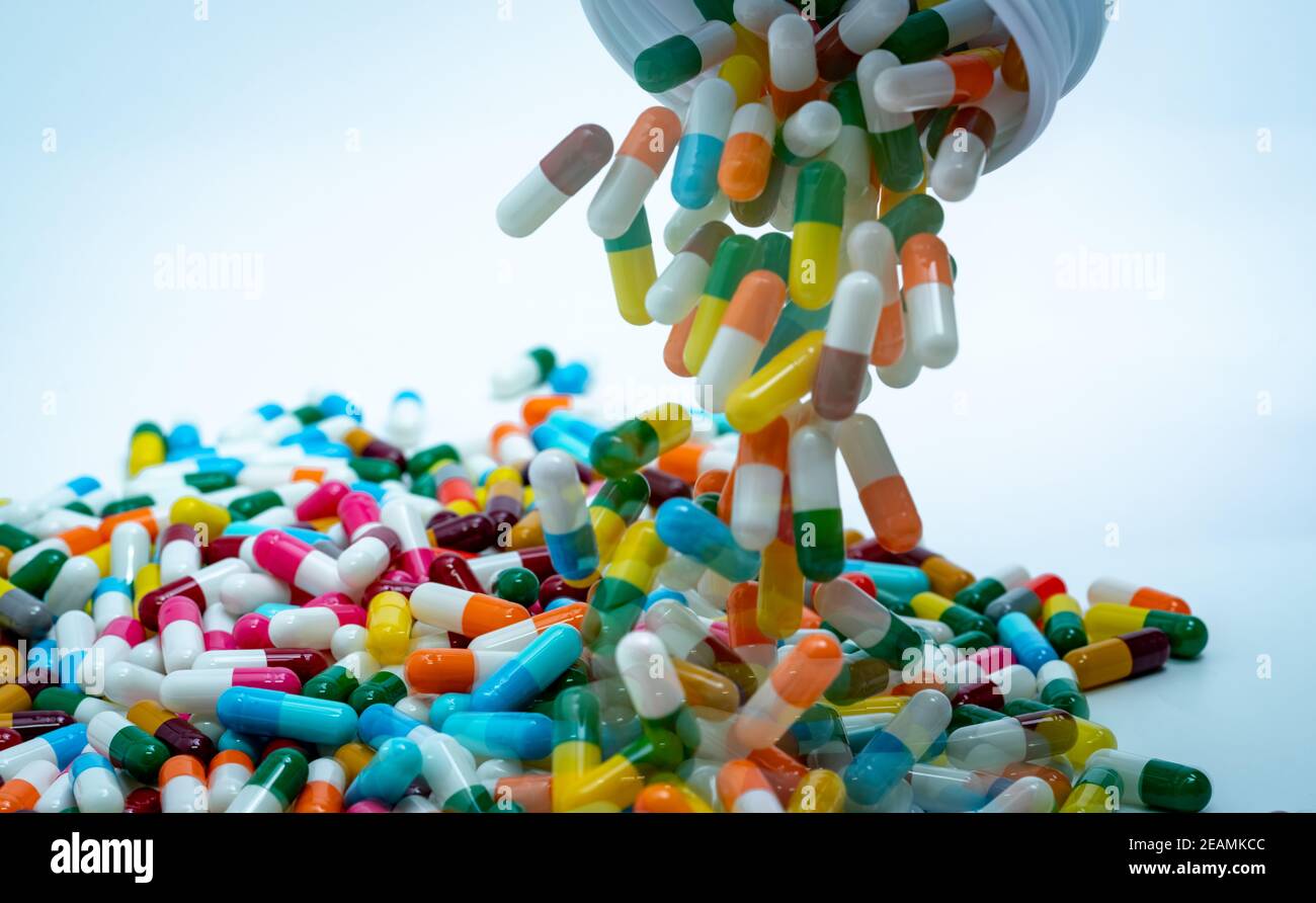 Pouring multicolored capsule pills from plastic drug bottle