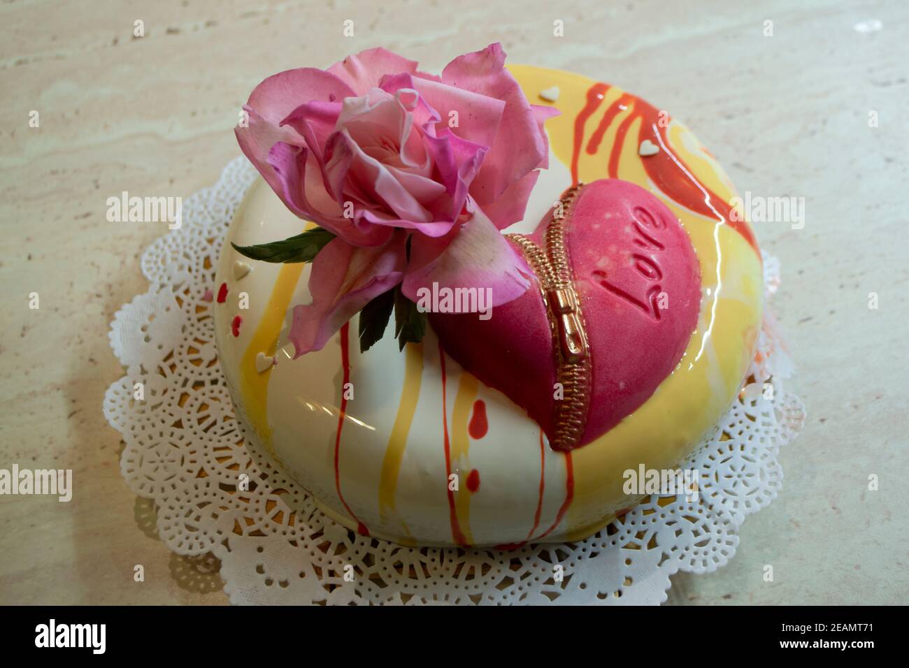 Contemporary multi layered mousse cake covered with mirror glaze with edible sugar rose and chocolate heart Stock Photo