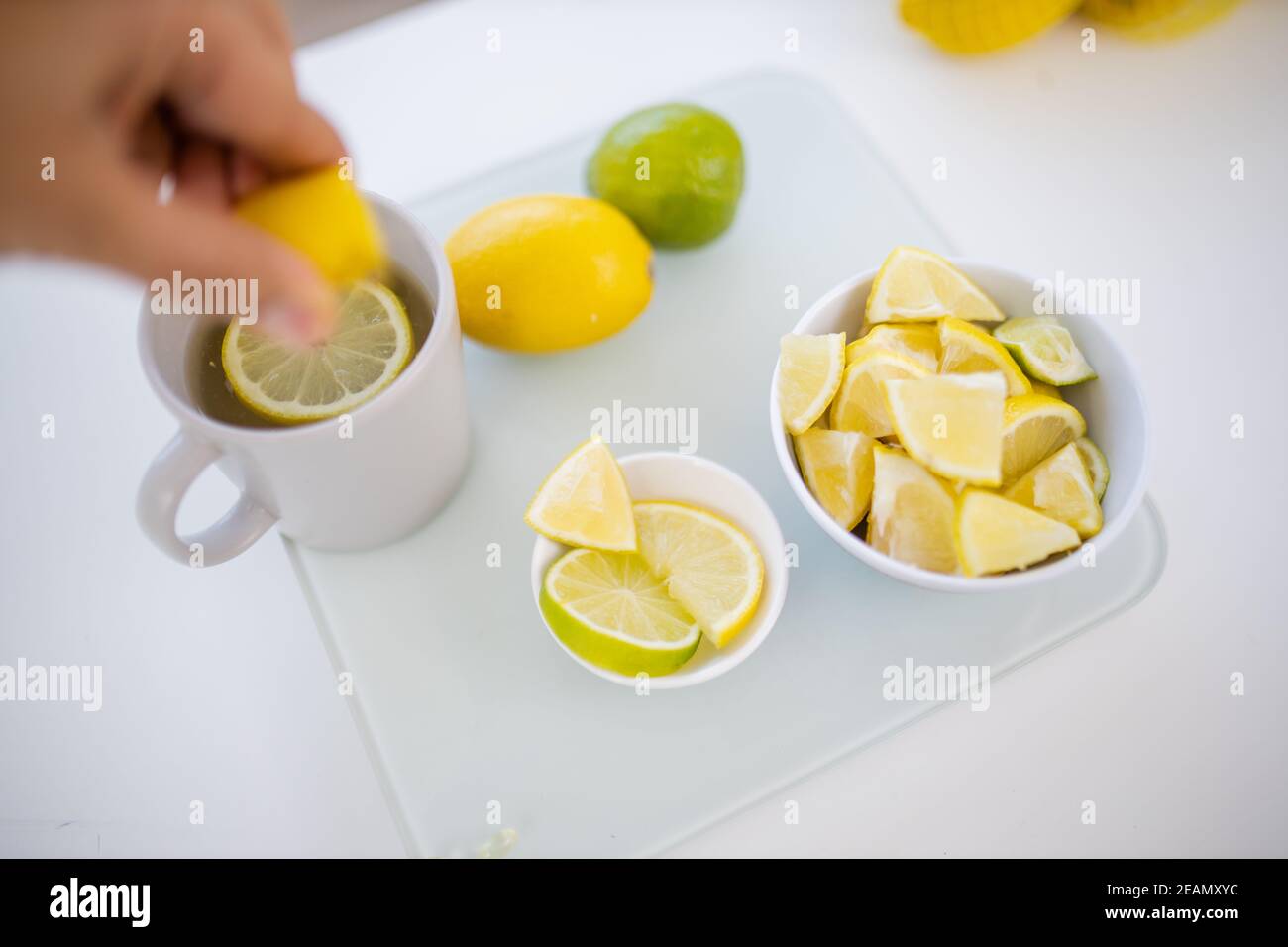 Female hand squeezing lemon into a cup of lemon tea Stock Photo Alamy
