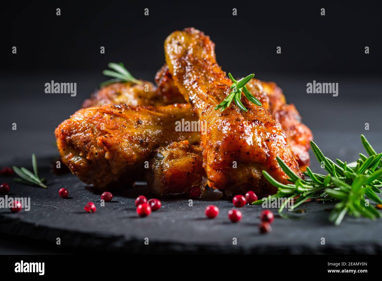 Hot spicy chicken legs with herbs on black background Stock Photo