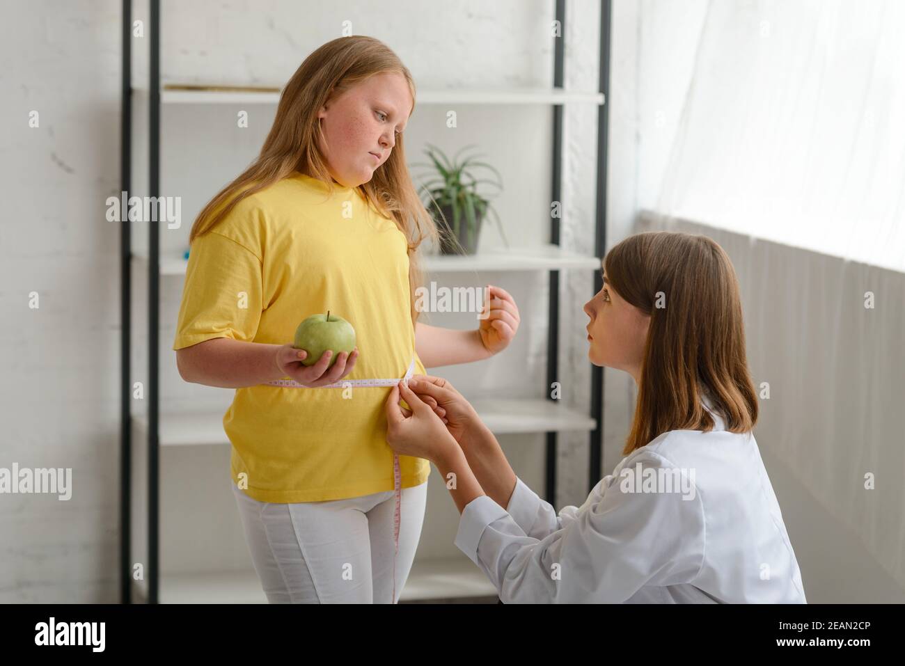 Nutritionist measuring obese girl's waist. Childhood obesity and weight loss Stock Photo