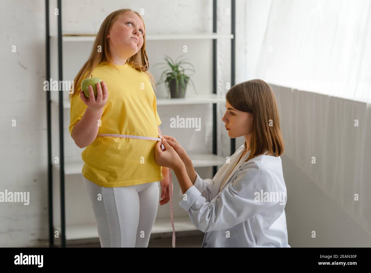 Nutritionist measuring obese girl's waist. Childhood obesity and weight loss Stock Photo