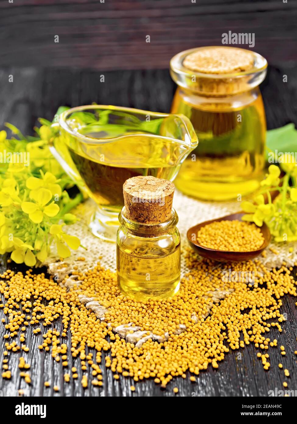 Oil mustard in two jars and gravy boat on dark wooden board Stock Photo