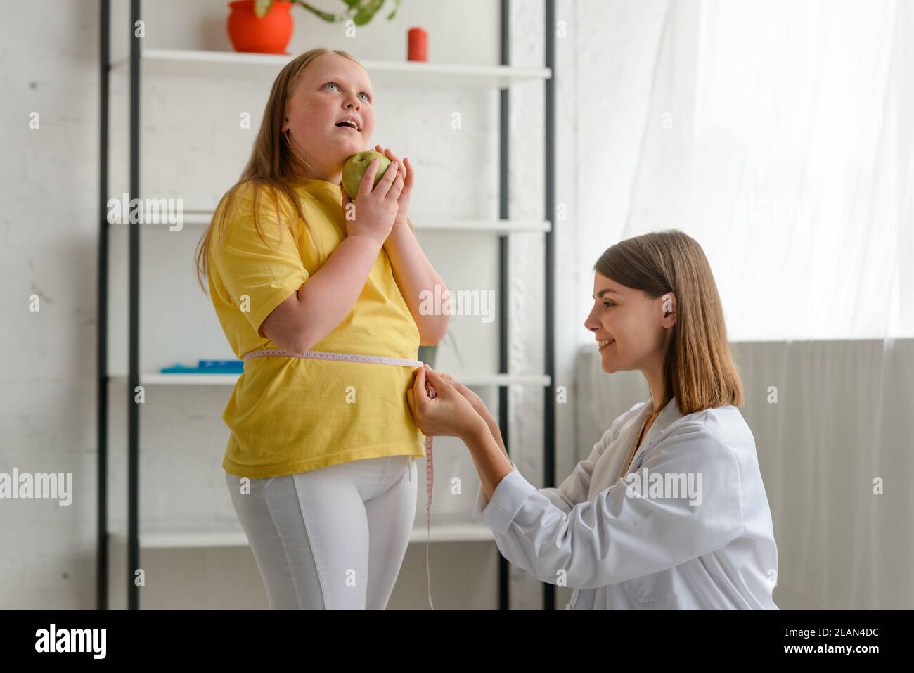 Young girl on weight loss program. Friendly doctor measuring her waist Stock Photo