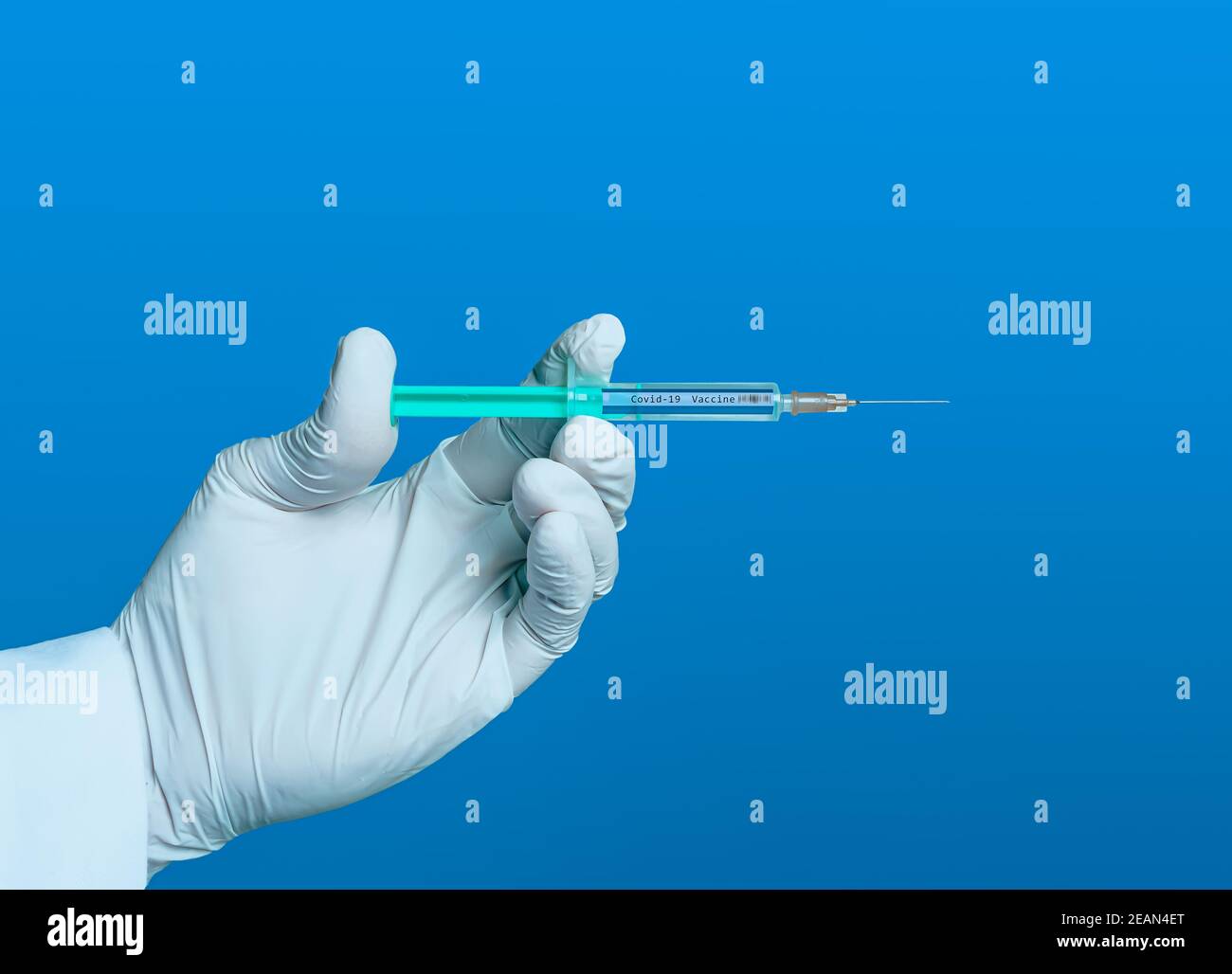hand with glove holds a syringe with the inscription covid 19 vaccine Stock Photo