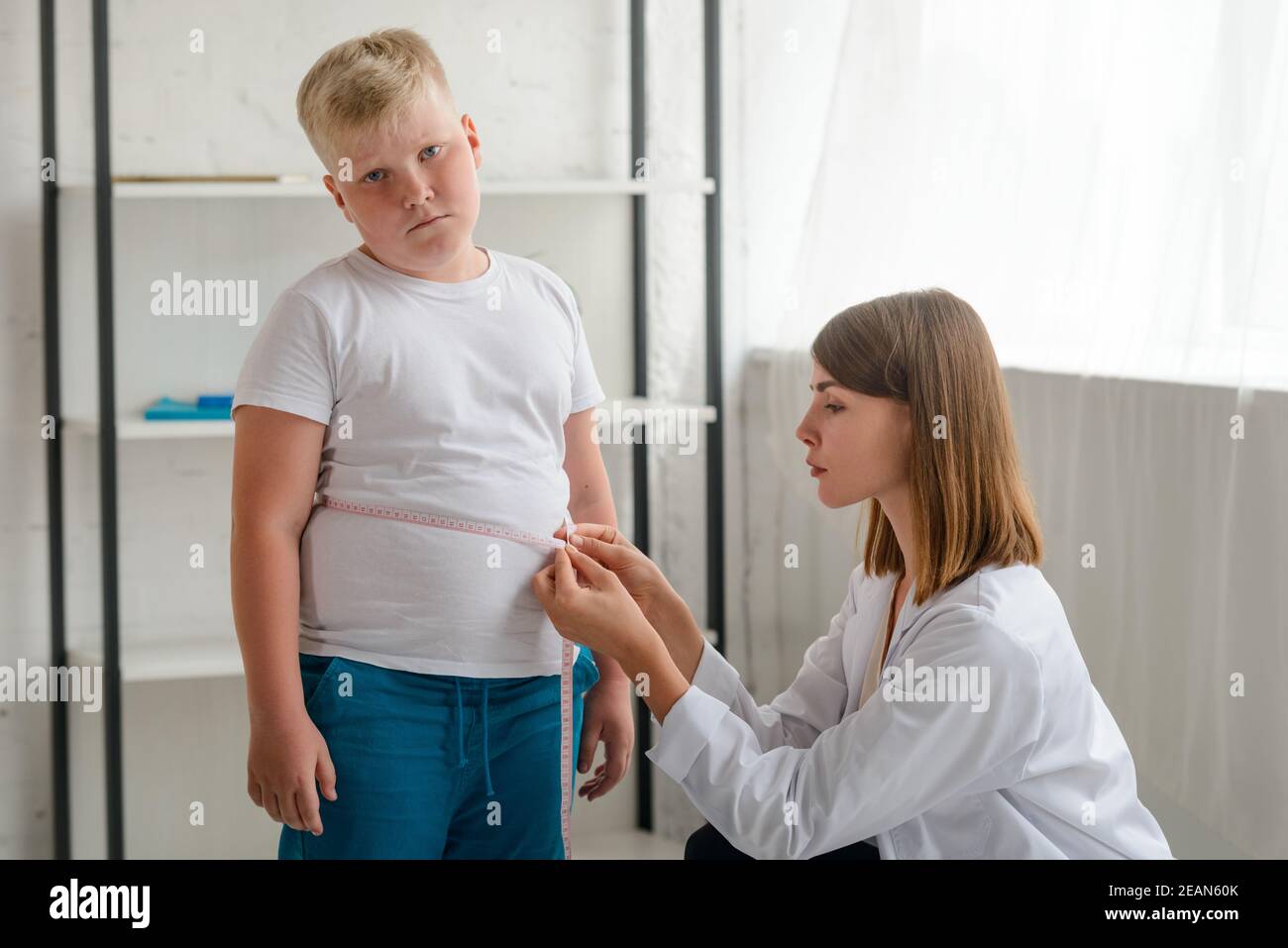 Upset boy during waistline measurement at a nutritionist's appointment Stock Photo