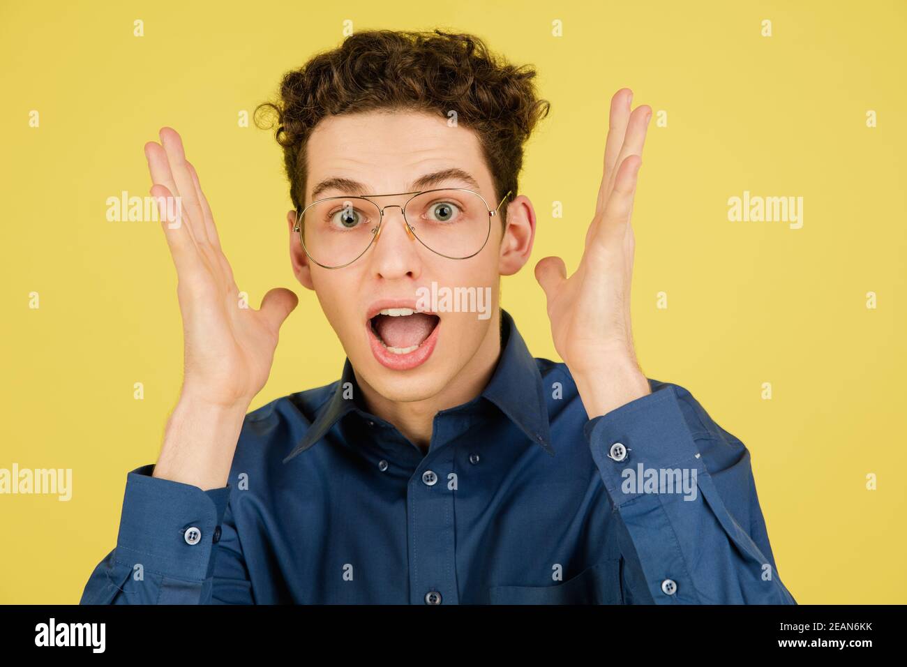 Astonished. Caucasian handsome man's portrait isolated on yellow studio background with copyspace. Male model with eyewear. Concept of human emotions, facial expression, sales, ad, fashion. Stock Photo