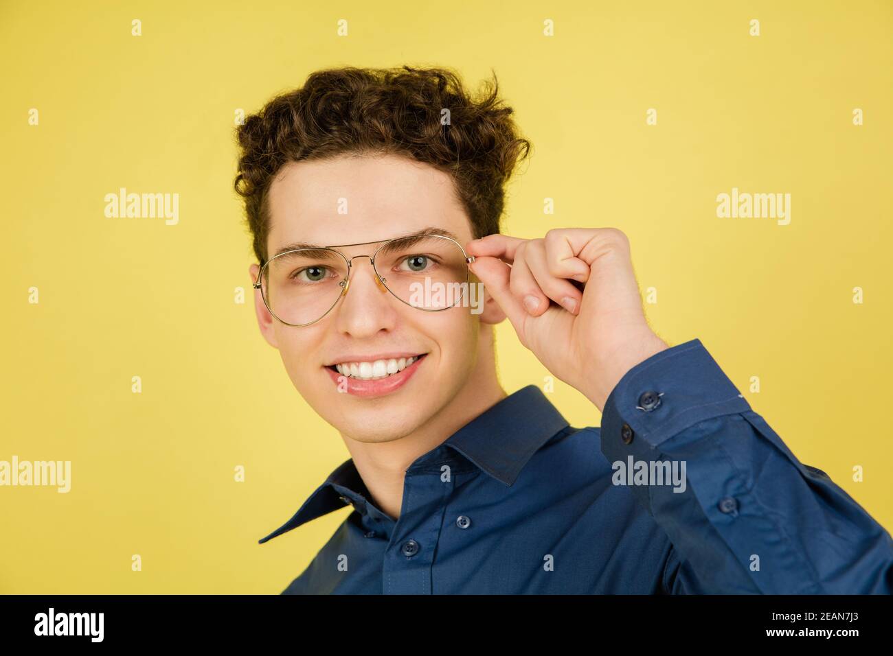 Smiling. Caucasian handsome man's portrait isolated on yellow studio background with copyspace. Male model with eyewear. Concept of human emotions, facial expression, sales, ad, fashion. Stock Photo