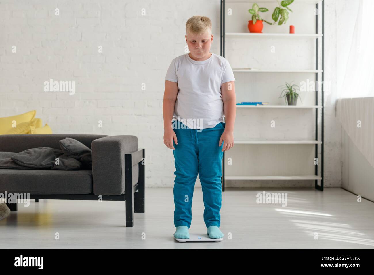 Obese boy disappointed after weighing and discovered that he gained weight Stock Photo