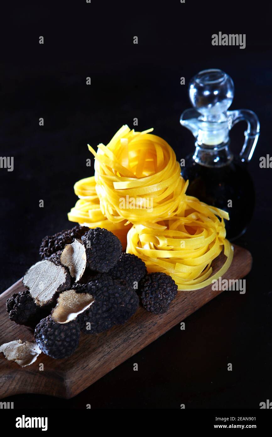 Black truffle on a wooden Board with nest paste and olive oil. The