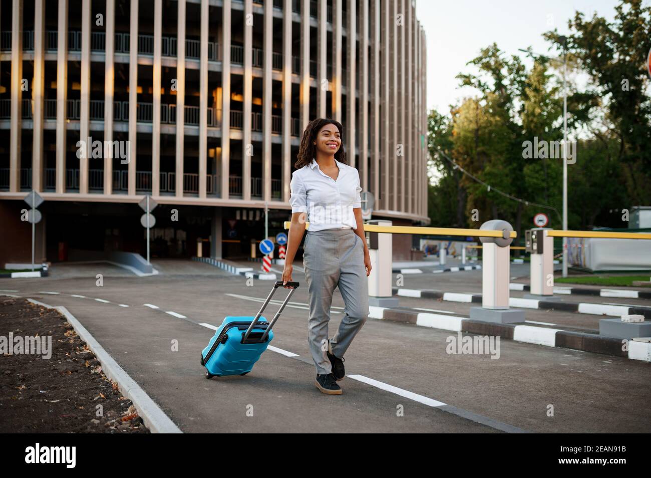 Woman with suitcase at the entrance to car parking Stock Photo