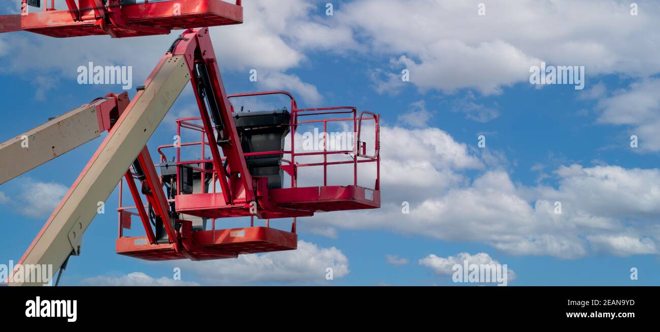 Articulated boom lift. Aerial platform lift. Telescopic boom lift against blue sky. Mobile construction crane for rent and sale. Maintenance and repair hydraulic boom lift service. Crane dealership. Stock Photo