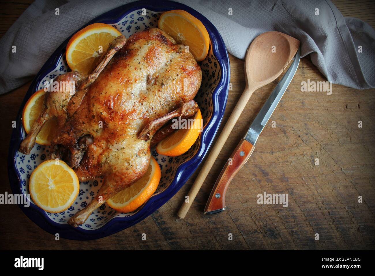 Whole crispy golden roast duck with fresh orange slices for a festive . Top view rustic wooden background Stock Photo