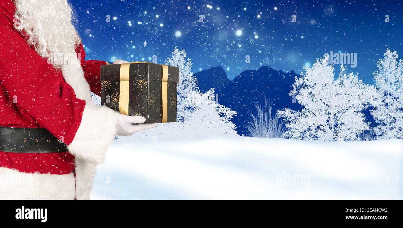 Santa holds a christmas gift in his hand in a wintry landscape Stock Photo