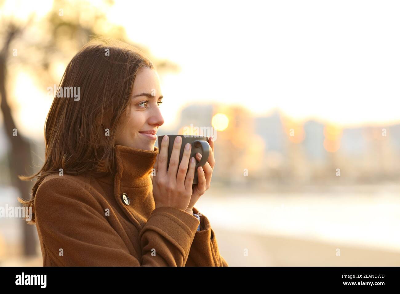 Woman drinking coffee on the beach in winter looking away Stock Photo