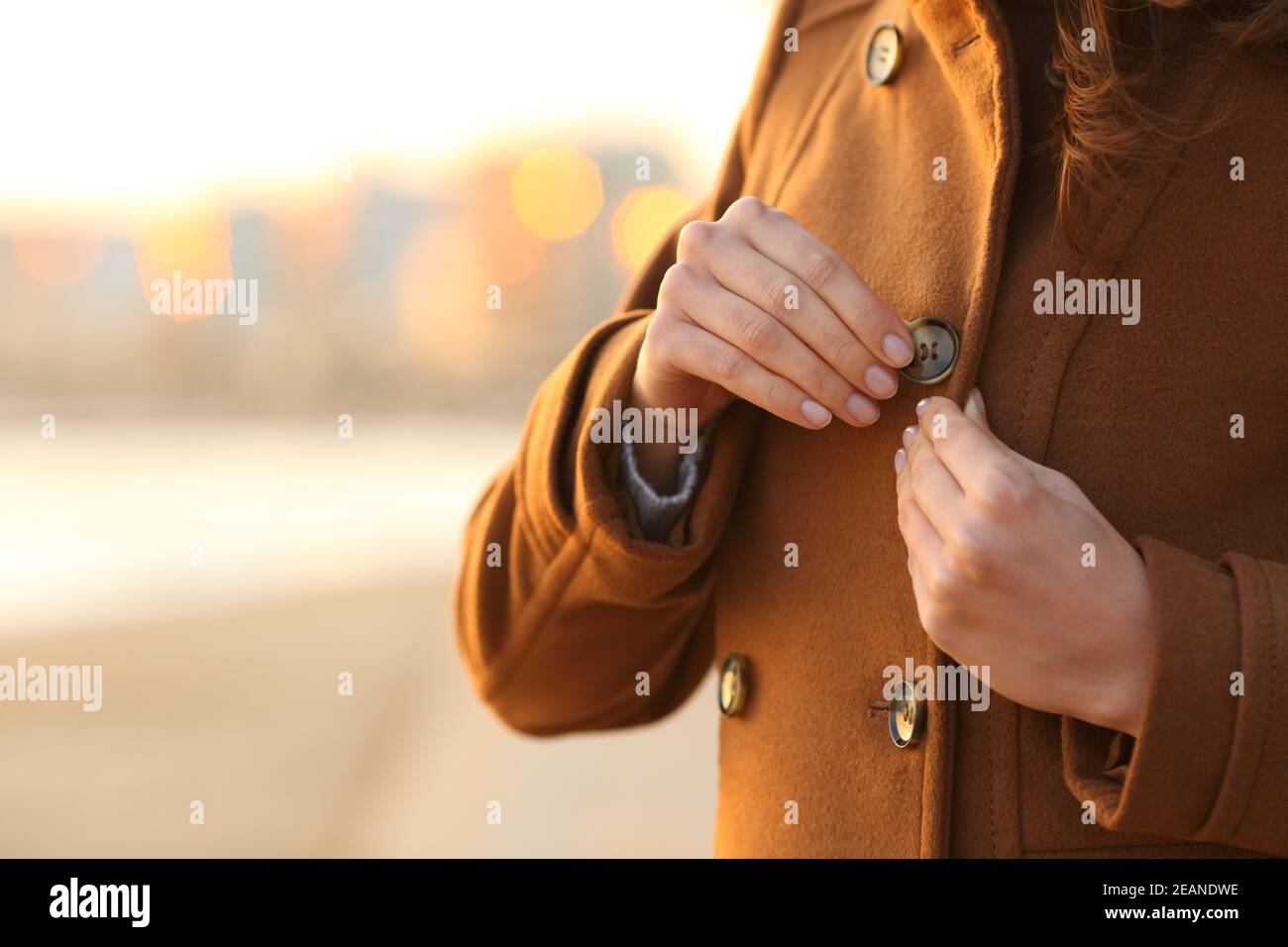 Lady fastening button of coat on the beach in winter Stock Photo