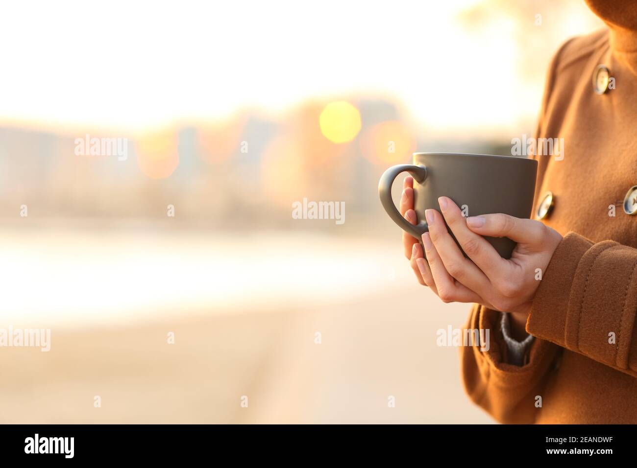 Woman hands holding coffee mug on the beach in winter Stock Photo