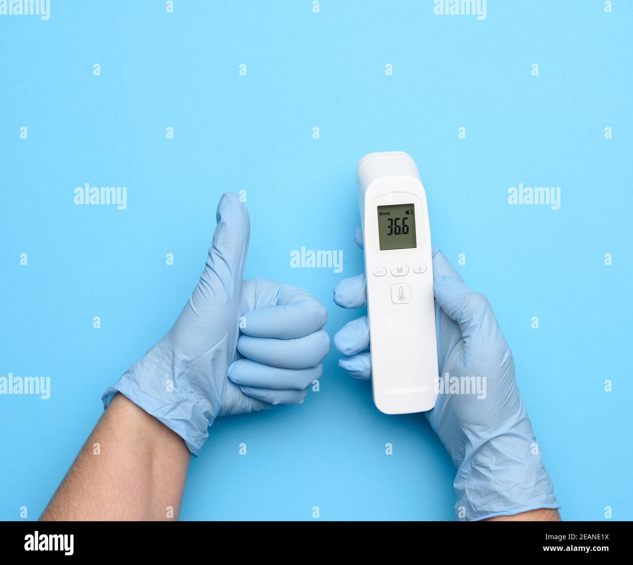 two hands in blue latex gloves hold an electronic thermometer to measure temperature Stock Photo