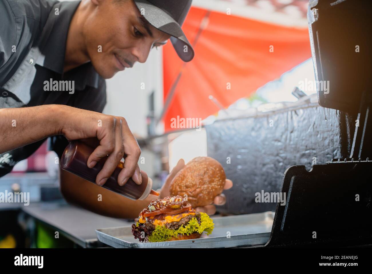Cook in a food truck or burger joint finishing a cheeseburger Stock Photo