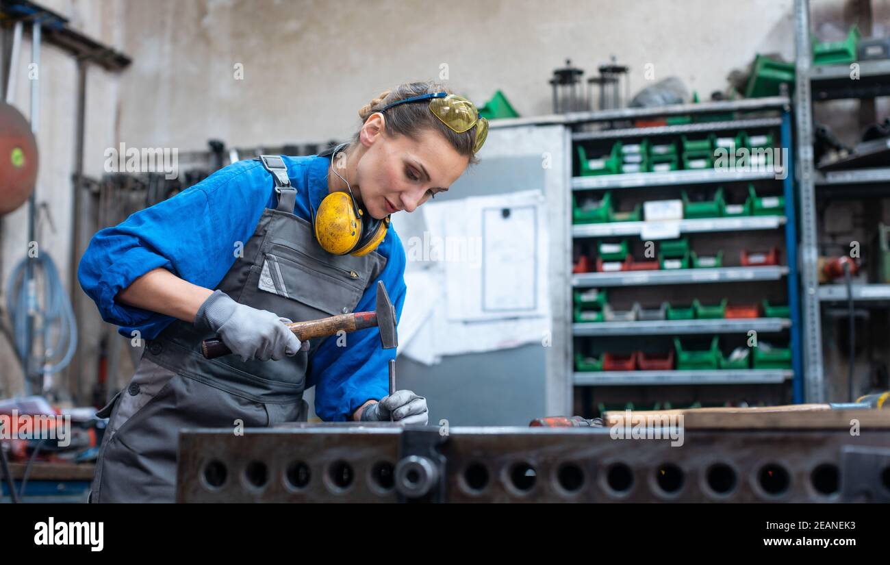 Woman metalworker marking piece of steel Stock Photo